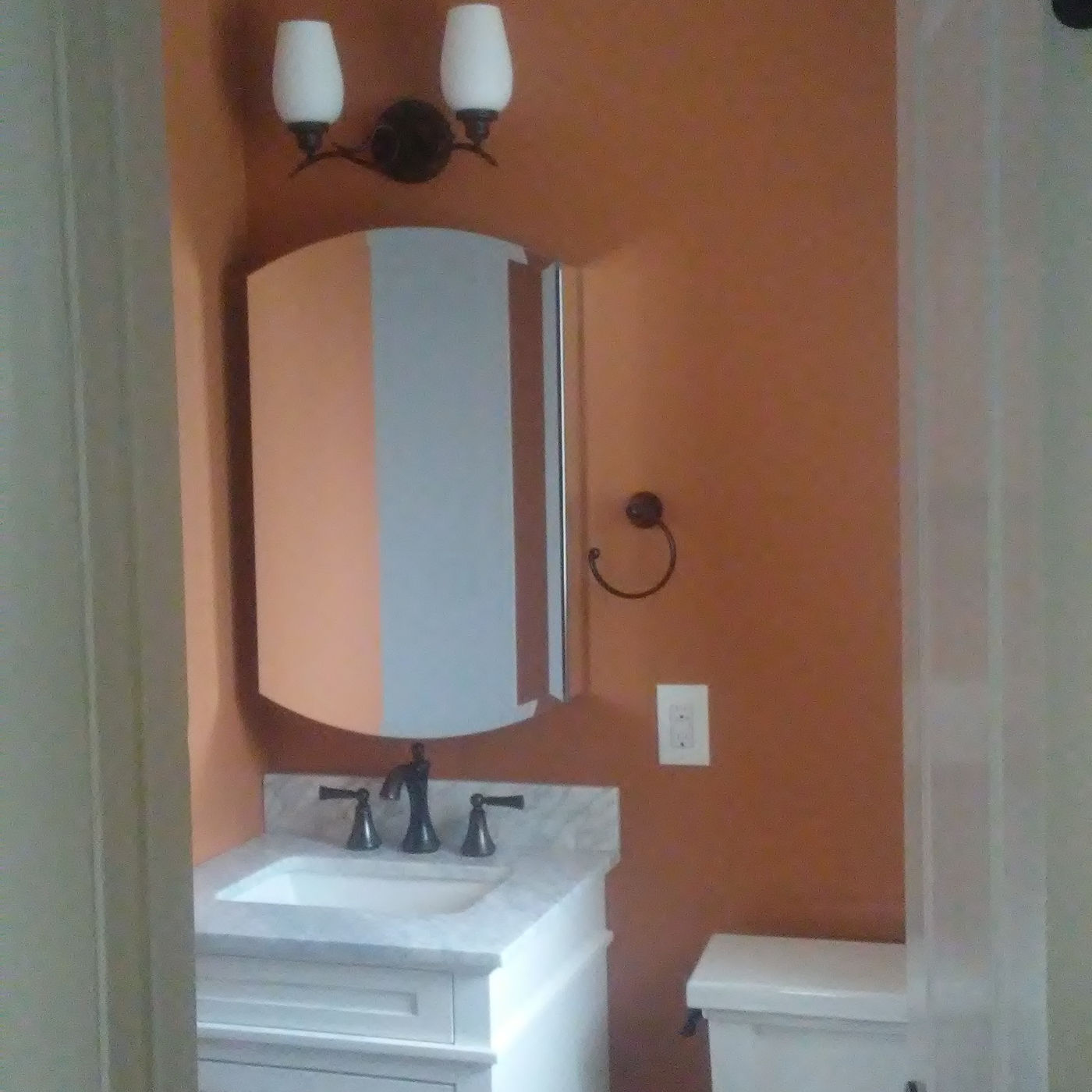 Small bathroom with a white vanity and terracotta walls