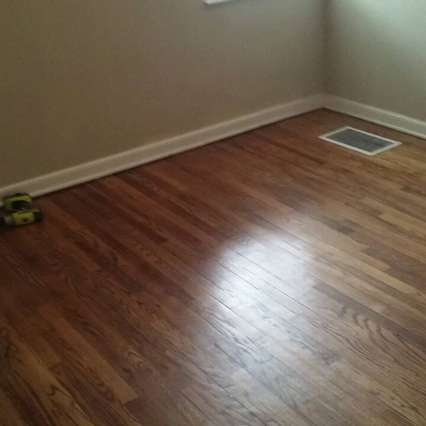 Hardwood floor corner with a drill on the boards