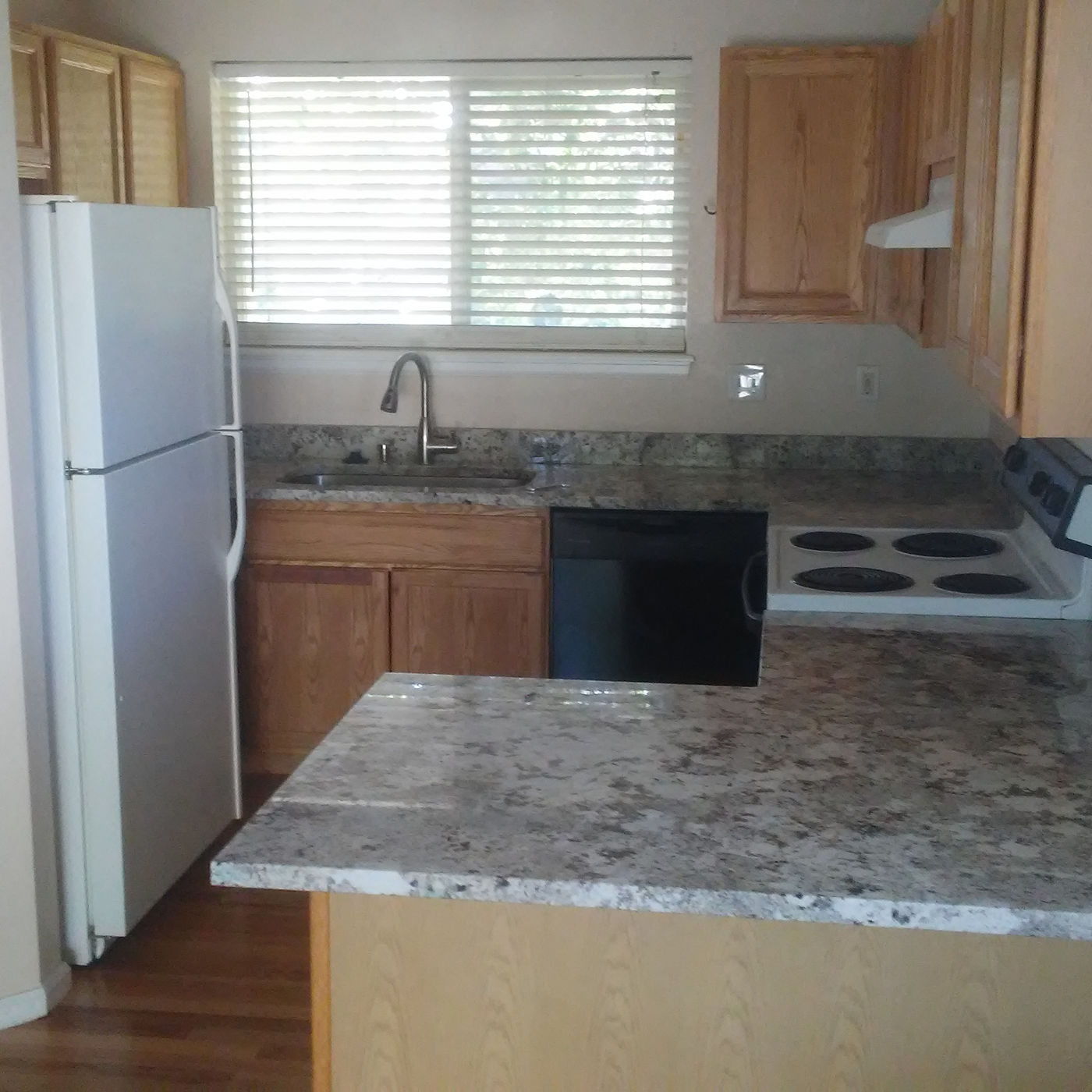 Kitchen with wood cabinets and a stone-look counter