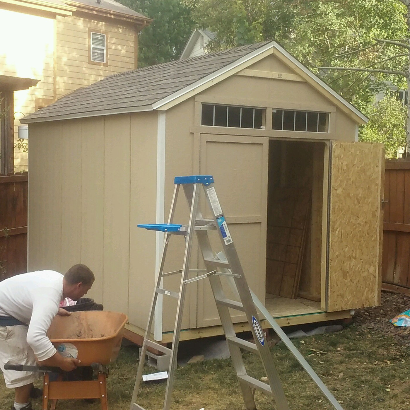 Garden shed going up in a backyard with a ladder and wheelbarrow