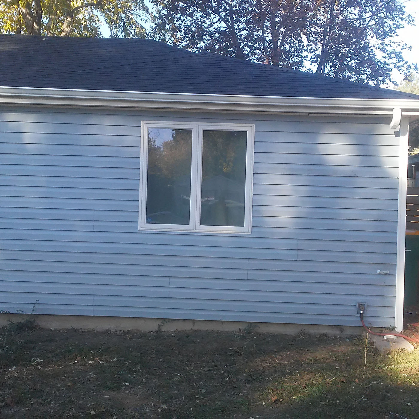 House wall with light blue lap siding, white trim, and a window